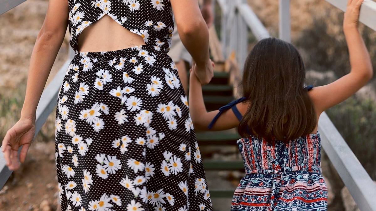 woman and girl walking on wooden stair during daytime